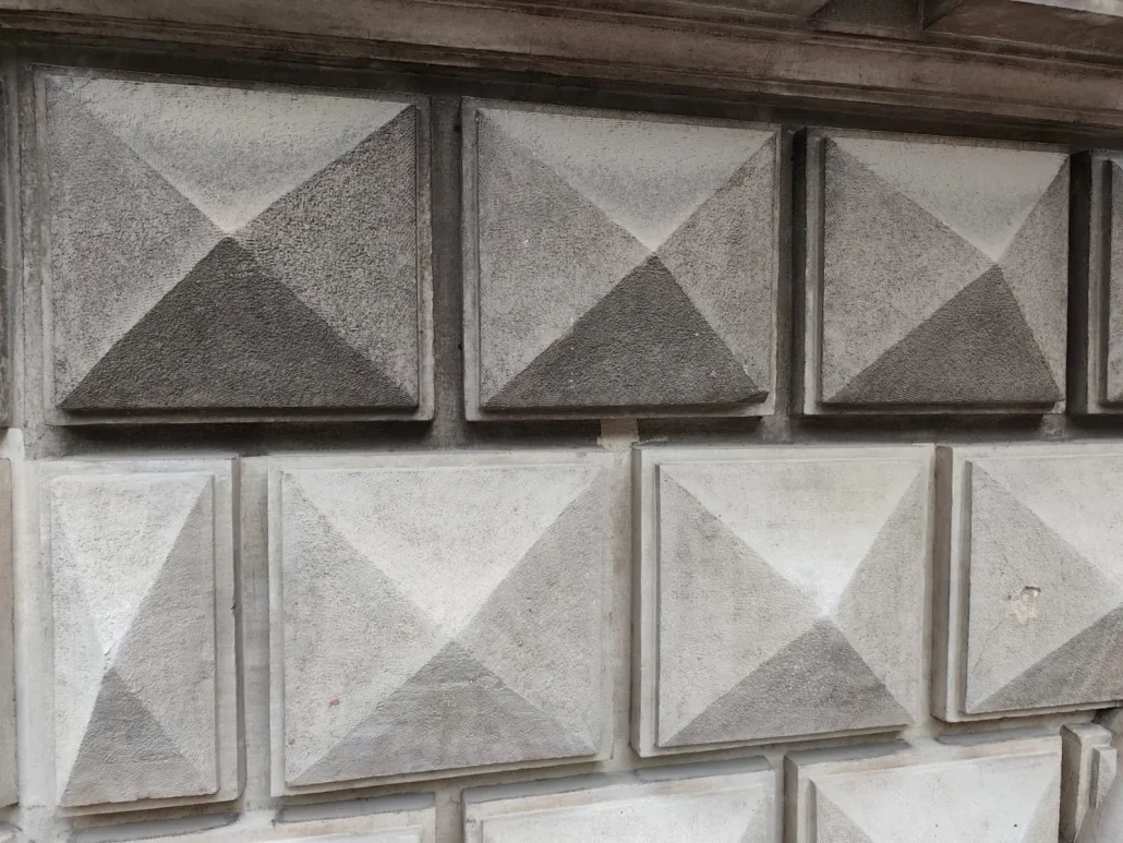 Fasadestein med pyramidemønster der noen felt er renset